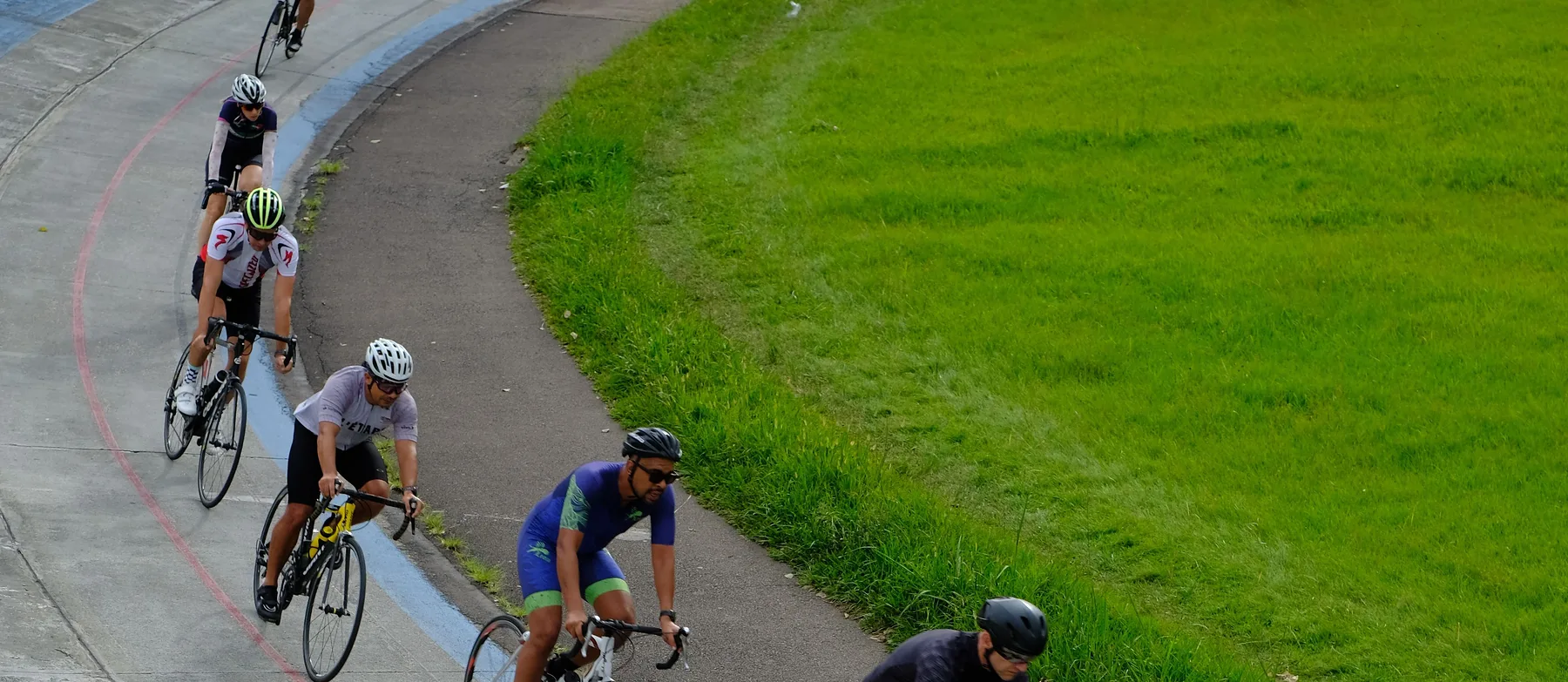 A line of road cyclists riding one behind the other along a smooth banked road