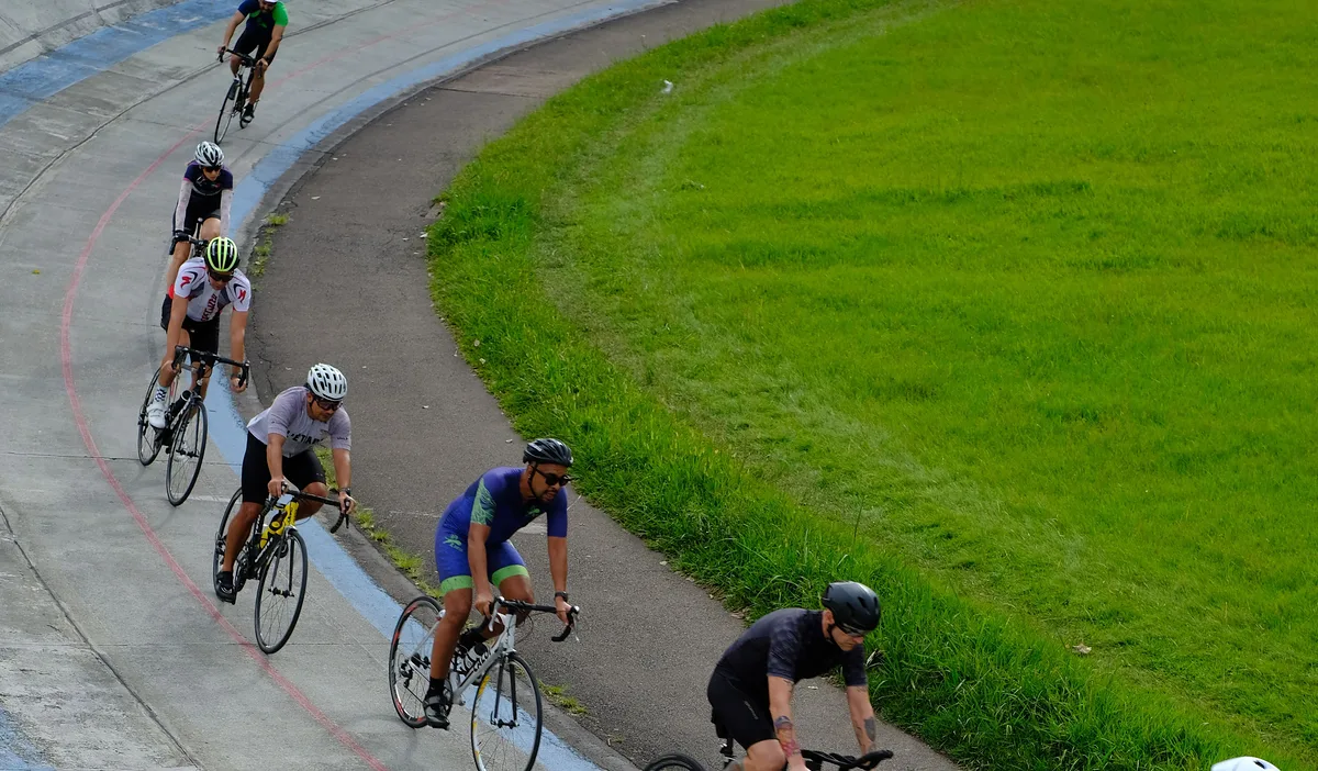 A line of road cyclists riding one behind the other along a smooth banked road