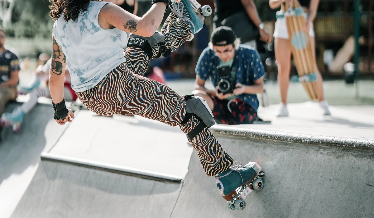A skater on wheels riding the smooth concrete wall of a park bowl